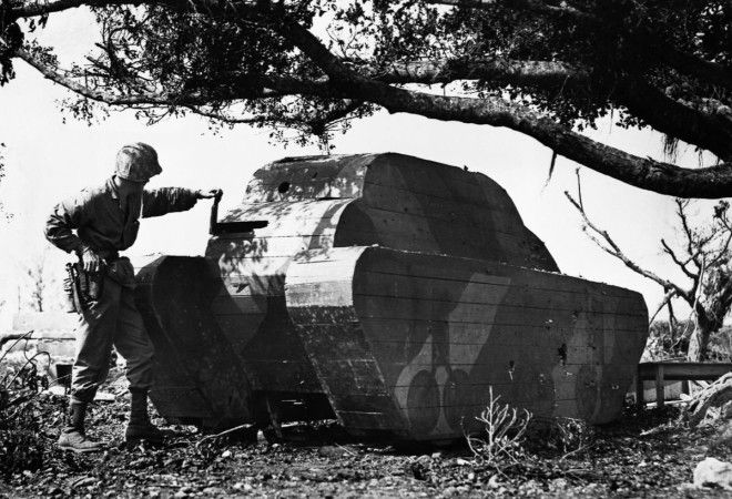 1945г Морской пехотинец армии США осматривает деревянную планку в муляже японского танка на Окинаве