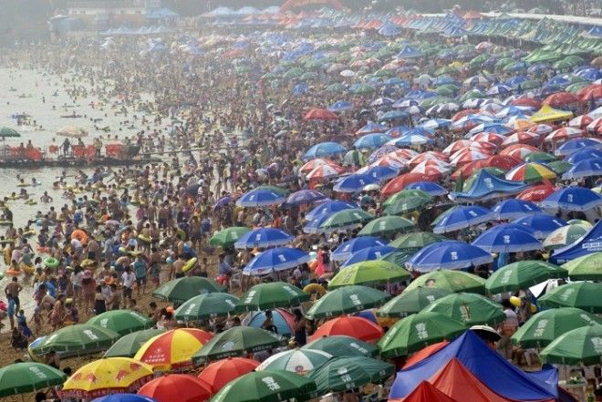 Люди толпятся на пляже в городе Далянь провинция Ляонин спасаясь от летней жары